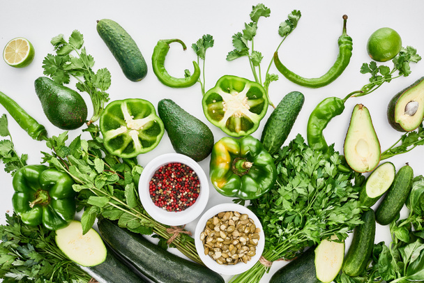 Blick von oben auf Kürbiskerne, Avocados, Gurken, Limetten, Paprika, Gewürze, Grün und Zucchini - Foto, Bild