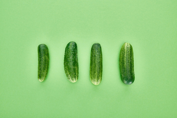 top view of fresh and whole cucumbers on green background  - Φωτογραφία, εικόνα
