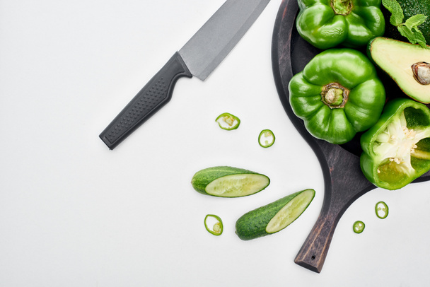 Blick von oben auf Messer, Avocado, Paprika, Gurken und Grün auf Pizza-Pfanne  - Foto, Bild