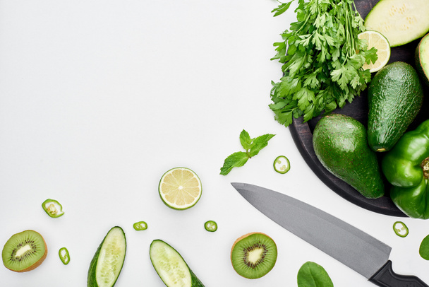 top view of knife, avocados, peppers, kiwi, limes and greenery on pizza skillet  - Photo, Image