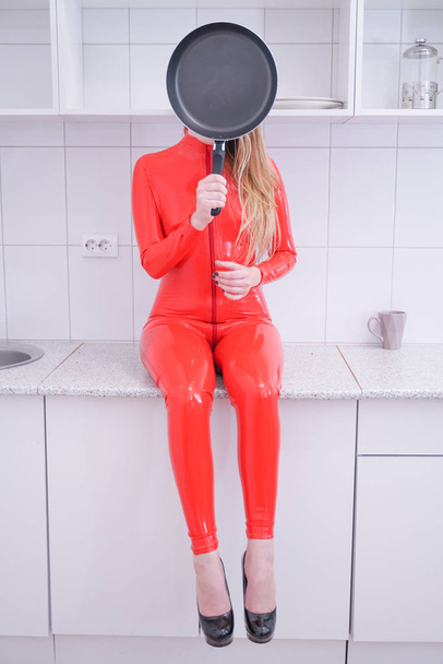 Женщина бьется сковородкой на белом фоне кухни
 - Фото, изображение