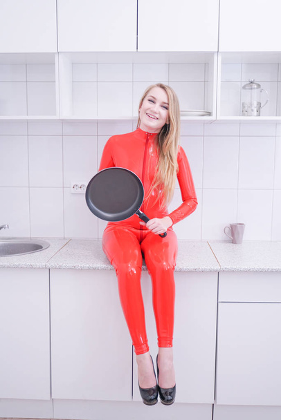 Woman beating with a frying pan on white kitchen background - Foto, Bild