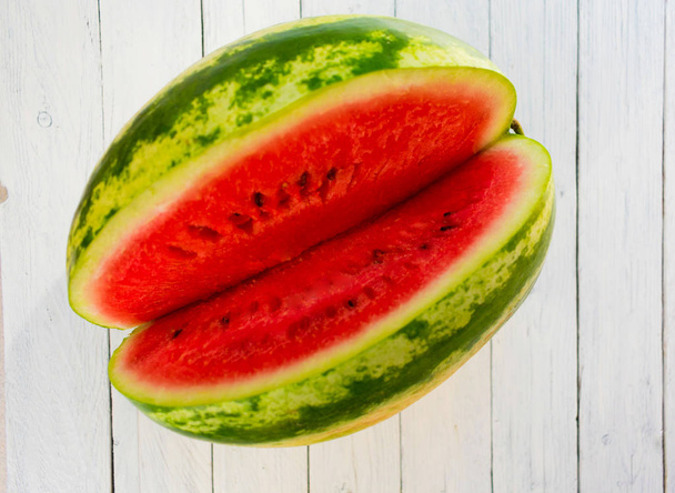  Čerstvě zralý proužkovaný meloun na bílém dřevěném pozadí. Pohled shora. - Fotografie, Obrázek