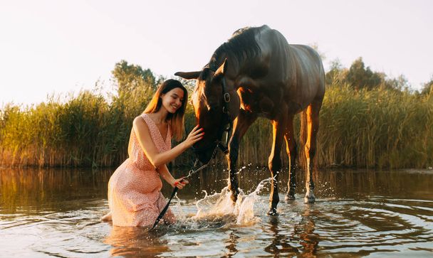 水に水しぶきを生み出す馬の隣に座る女性 - 写真・画像