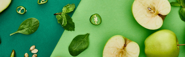 Panoramaaufnahme von Paprika, Äpfeln, Kürbiskernen auf grünem Hintergrund  - Foto, Bild