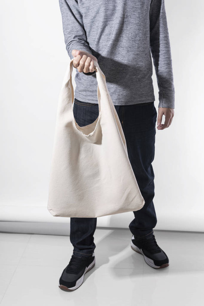 Man is holding bag canvas fabric for mockup blank template on white background. global warming concept. - Photo, Image
