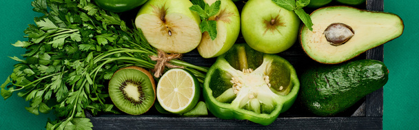 panoramic shot of apples, avocados, pepper, kiwi, greenery, lime in wooden box - Photo, Image