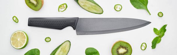 panoramic shot of knife, fresh cucumbers, kiwi, lime, peppers and greenery  - Fotoğraf, Görsel