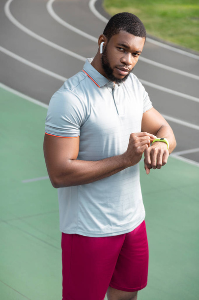 Athlete keeping his hand on a fitness tracker - Foto, imagen