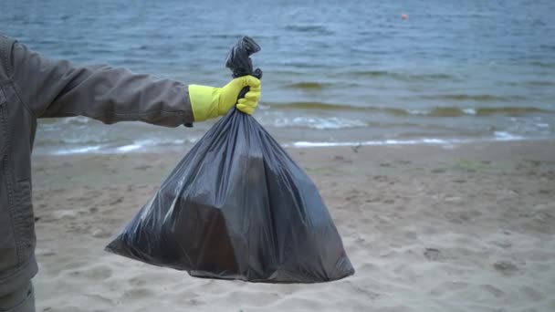 önkéntes kezek szemeteszsákot tartó strandon - Felvétel, videó