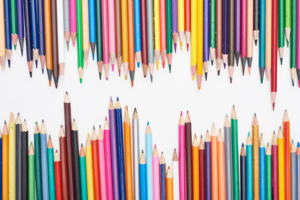 Two lines of different sizes color pencils isolated on white - 写真・画像