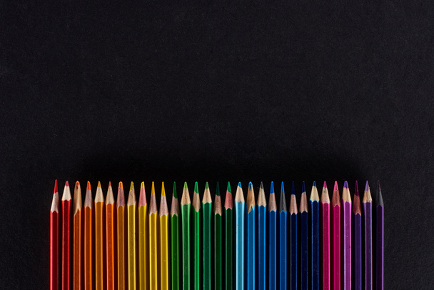 Regenboog spectrum gemaakt met rechte rij kleurpotloden geïsoleerd op zwart - Foto, afbeelding