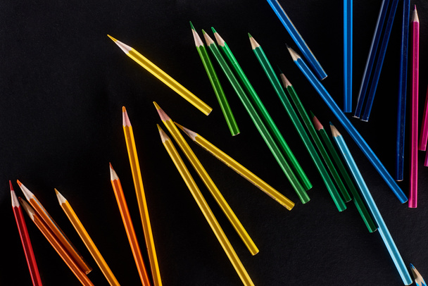 Scattered sharpened color pencils isolated on black - 写真・画像