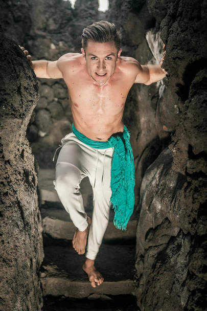 Energetic man with naked torso rising up from cave - Photo, Image