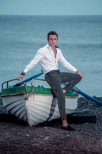 Hombre pensativo de moda apoyado en el barco de remos
 - Foto, imagen