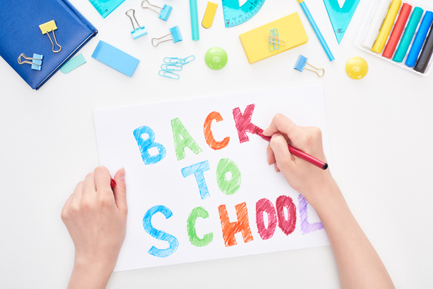 Cropped image of schoolgirl holding card with back to school lettering isolated on white - Photo, Image