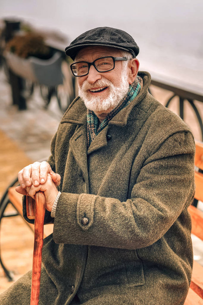 Portret uśmiechniętego starszego mężczyznę siedzącego na ławce w parku - Zdjęcie, obraz