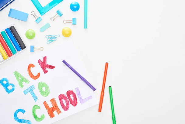Renkli keçeli kalemlerin ve beyaz üzerine izole edilmiş okul malzemelerinin yanında okul metnine arka arkaya kağıt görünümü - Fotoğraf, Görsel