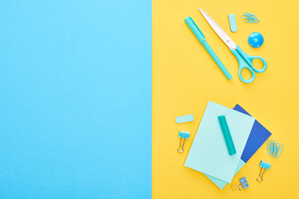 Top view of different blue stationery with sheets of paper on bicolor background - Foto, Imagem