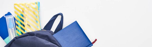 Foto panorámica de mochila azul con bloc de notas, estuche de lápiz y útiles escolares aislados en blanco
  - Foto, Imagen