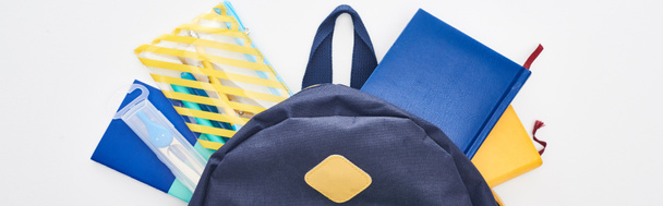 Tiro panorâmico de saco escolar azul com blocos de notas e estojo de lápis isolado em branco
  - Foto, Imagem