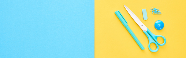 Panoramic shot of blue pen, scissors and paperclips on bicolor background - Фото, изображение