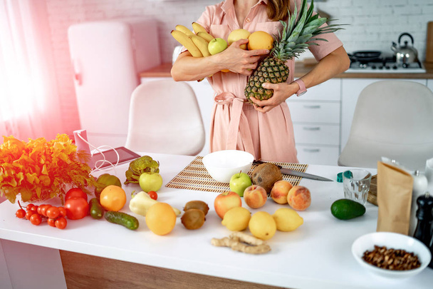 Happy woman with fruits and vegetables in the kitchen. Healthy food and Dieting concept. Loosing Weight - 写真・画像