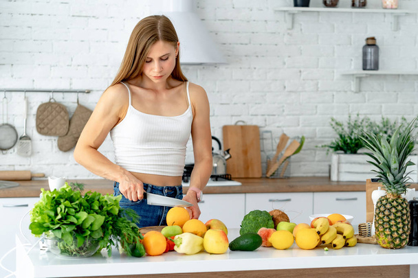 Cute healthy girl with fruits and vegetables in kitchen. Healthy food and Dieting concept - Фото, изображение