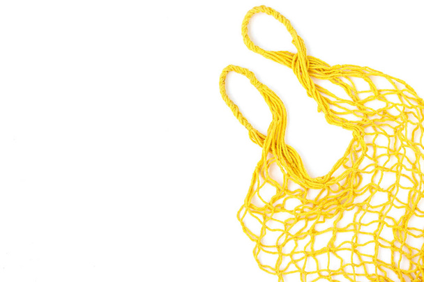 Empty shopping yellow mesh bag on white background, horizontal orientation, Zero waste concept, copy space - Photo, Image
