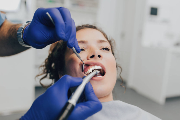 Mooie jonge vrouw met tandheelkundige behandeling in het kantoor van de tandarts.  - Foto, afbeelding