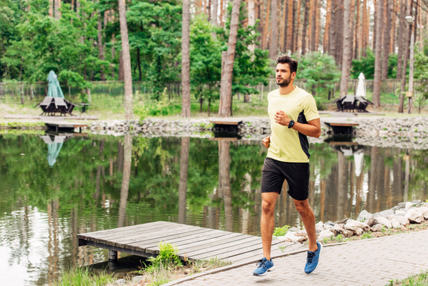 apuesto deportista corriendo en la pasarela cerca del lago
  - Foto, imagen
