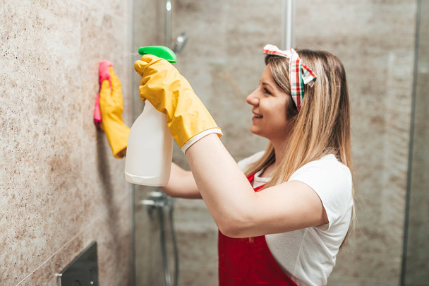 Fiatal és boldog nő takarítás ház fürdőszoba. - Fotó, kép