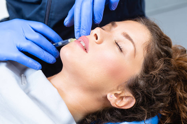 Ιατρική διαδικασία στα χείλη της γυναίκας με υαλουρονικό οξύ. - Φωτογραφία, εικόνα