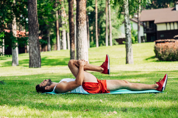 Profil Brodaty Athletic człowiek pracuje na mat fitness w parku  - Zdjęcie, obraz