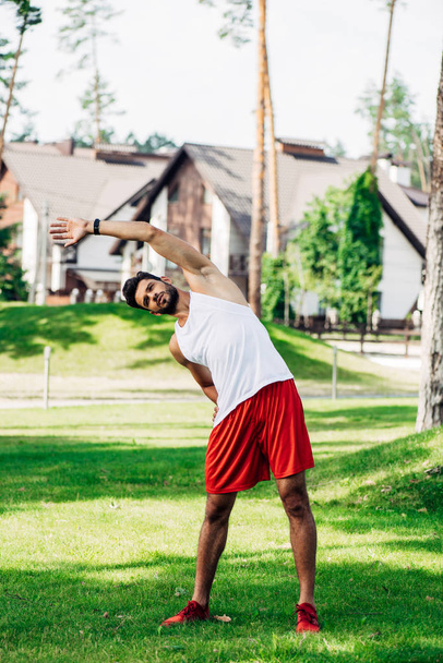 deportista atlético barbudo haciendo ejercicio en el césped verde
  - Foto, imagen