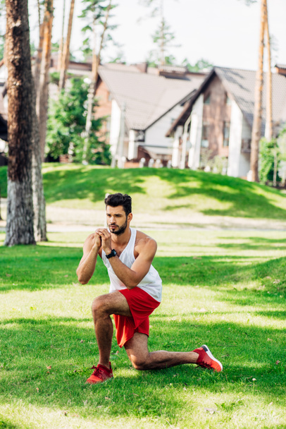 handsome man working out on green lawn near buildings  - Foto, Imagen