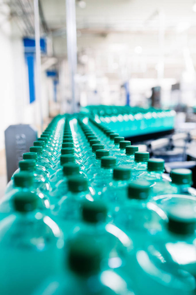 Şişeleme tesisi - Yeşil şişelere gazlı suyun işlenmesi ve şişelenmesi için su şişeleme hattı. Seçici odaklama.  - Fotoğraf, Görsel