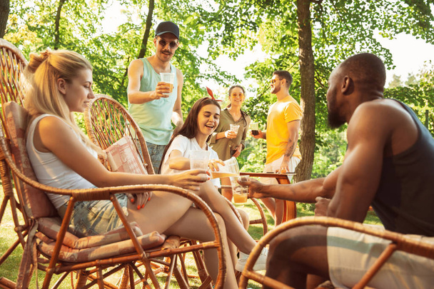 Amigos felices dan una fiesta de cerveza y barbacoa en un día soleado
 - Foto, Imagen