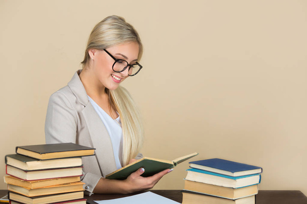  beautiful young woman in glasses and in a suit sits at a table with books - Фото, зображення