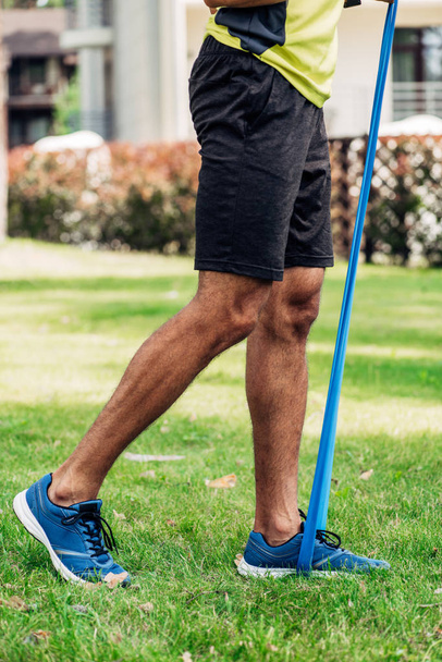 Ausgeschnittene Sicht auf Mann, der mit Halteschlaufen im Park trainiert  - Foto, Bild