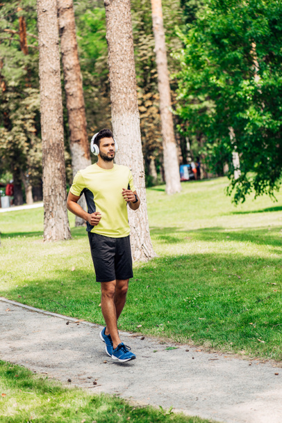 handsome bearded man running while listening music in headphones  - Foto, immagini