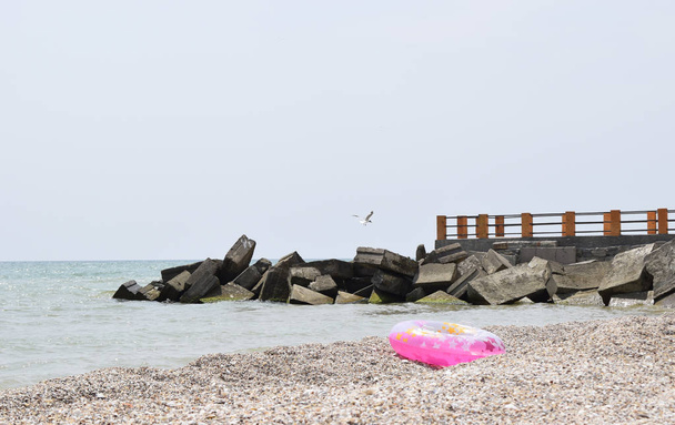 Морской пирс. Морской горизонт и резиновое кольцо на пляже
 - Фото, изображение