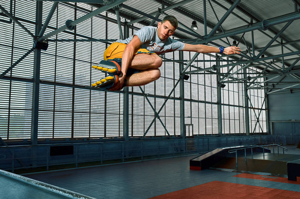 Rollerblader sauter haut de la grande rampe d'air performant tour. Équipement de skate park intérieur
. - Photo, image