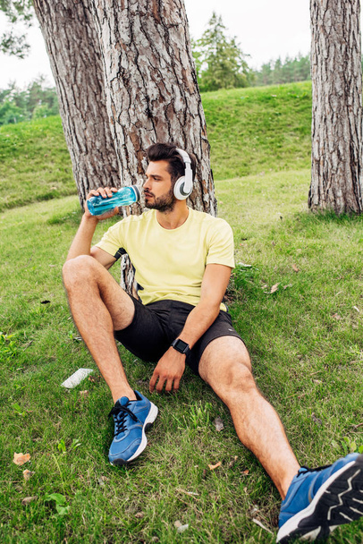 selective focus of handsome man drinking water near trees  - Fotoğraf, Görsel