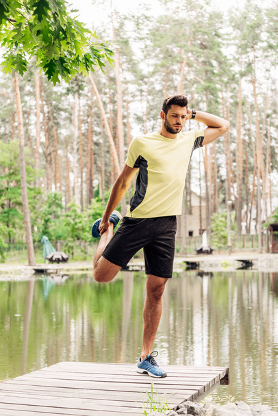 homme athlétique en vêtements de sport faisant de l'exercice près du lac en forêt
  - Photo, image