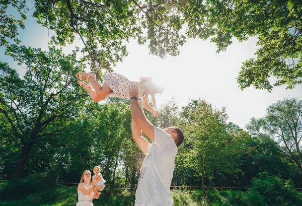 Papá vomita a su hija en el aire. Feliz familia pasando tiempo juntos en el parque de verano
. - Foto, imagen