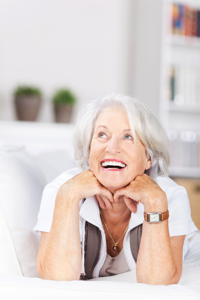Laughing senior woman lying on a sofa - Foto, afbeelding