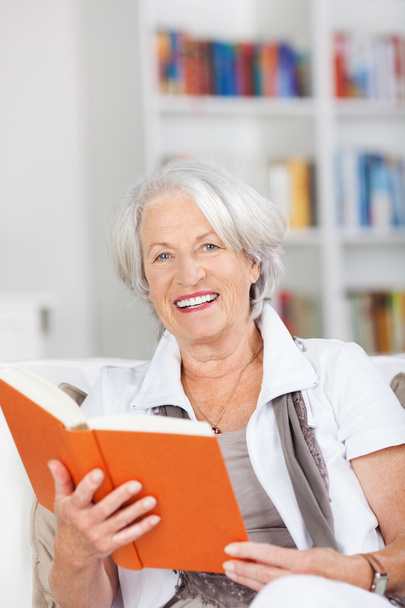 Senior Woman Holding Book While Sitting On Sofa - Foto, Imagem