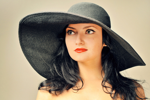 Porträt der attraktiven dunkelhaarigen sinnlichen jungen schönen Frau mit schwarzem Hut mit breiter Krempe - Foto, Bild