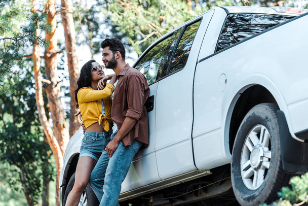 low angle view of attractive girl in sunglasses standing with bearded man near car   - Fotoğraf, Görsel
